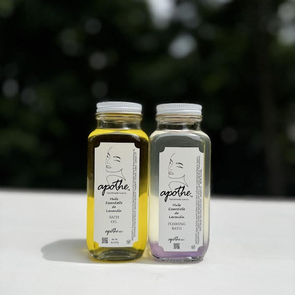 Two bottles of apothe bath products on a white surface with a blurred green background