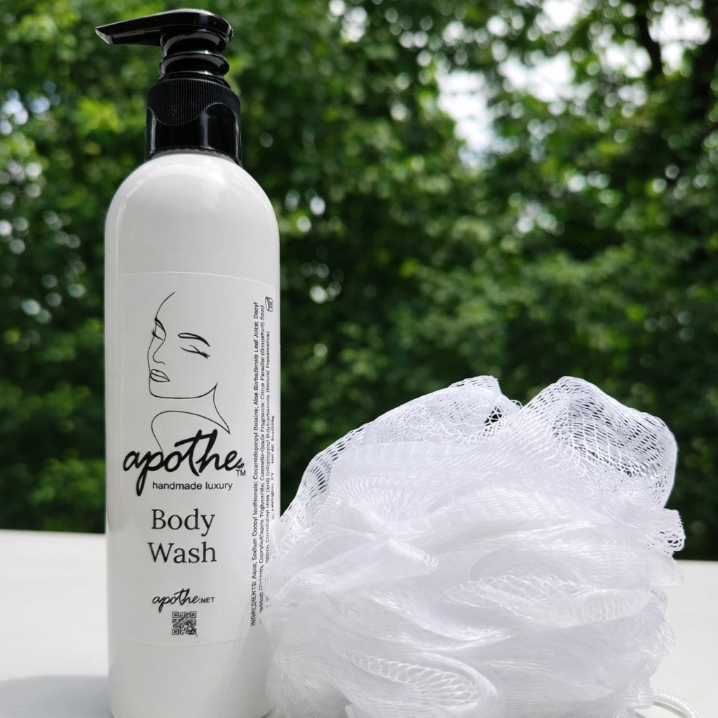 Body wash bottle with a loofah on a white surface with a green blurred background