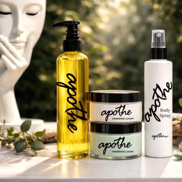Apothe skincare products including a bottle of golden oil, white body spray bottle, jars of white body butter and mint green skin polish.